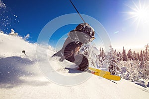 Skier skiing downhill during sunny day fresh snow freeride. Extreme High speed, frosty dust scatters