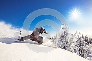 Skier skiing downhill during sunny day fresh snow freeride. Extreme High speed, frosty dust scatters