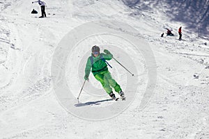 Skier skiing downhill during sunny day in high mountains