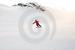 Skier skiing downhill during sunny day in high mountains