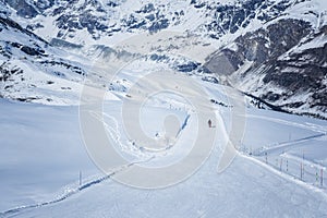 Skier skiing with helmet alone on the ski slope towards Matterhorn mountain on a beautiful sunny day in Switzerland