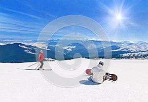 Skier and snowboarder skiing downhill in mountains, winter sport