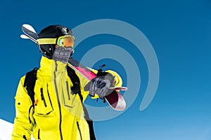 Skier standing on a slope. Man in a light suit, the helmet and mask in skiing is to ski. In the background snow-capped