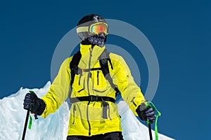 Skier standing on a slope. Man in a light suit, the helmet and mask in skiing is to ski. In the background snow-capped