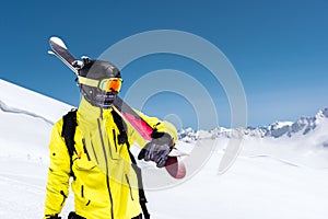 Skier standing on a slope. Man in a light suit, the helmet and mask in skiing is to ski. In the background snow-capped