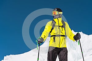 Skier standing on a slope. Man in a light suit, the helmet and mask in skiing is to ski. In the background snow-capped