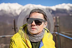 Skier in sunglasses with the reflection of snowy mountains.