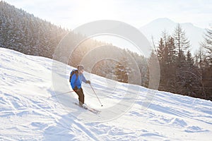 Skier in sunset mountains, downhill skiing