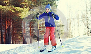 Skier teenager boy skiing in winter forest on snowy background