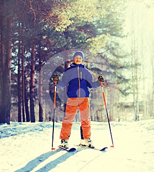 Skier teenager boy skiing in winter forest on snowy background