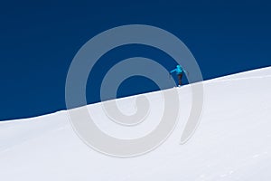 Skier touring up a snow covered alpine ridge in winter