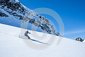 Skier on untouched powder slope under blue skies