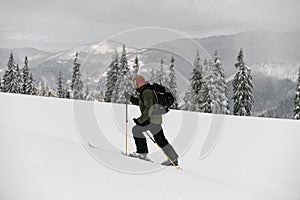 skier walking on ski along snowy trail with backpack. Ski touring