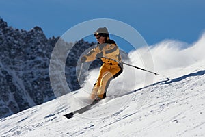 Skier woman in yellow suite moving down on slope