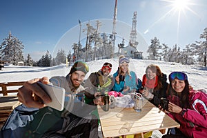 Skiers in cafe on ski terrain taking selfie