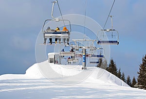 Skiers in chairlift arriving to top of mountain