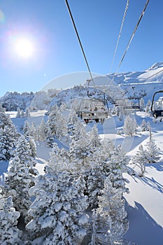 Skiers on the chairlift mounting on the top of the slopes