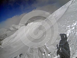 Skiers climb the trail on snow-capped top