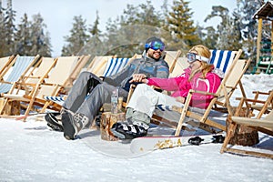 Skiers couple in sun lounger enjoy on sun