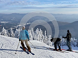 Skiers getting ready to ski down the slopes at beautiful snow day at the Stowe Mountain Ski resort