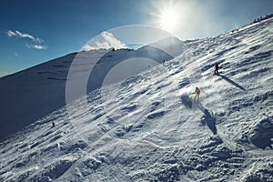 Skiers go down the snowy mountain hill