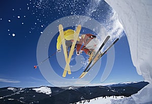 Skiers Launching Off Snow Bank Hitting The Slopes photo