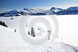 Skiers on ski lift enjoying the view to foggy Alps in Austria and beautiful snowy country panorama in famous Kitzbuehel mountain