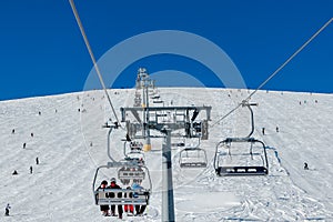 Skiers on a ski lift and piste