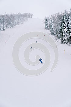 Skiers ski on a snowy track along a steep slope