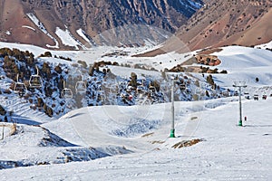 Skiers and snowboarders goes up on ski lift, leading to top of slope. Resort