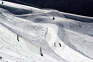 Skiers and snowboarders riding on a ski slope in mountain resort snowy winter