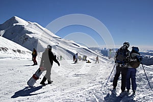 Skiers and snowboarders riding on a ski slope in mountain resort snowy winter