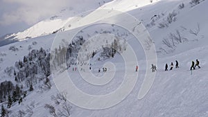 Skiers And Snowboarders Skiing Down Snowy Ski Slope In Mountains In Winter