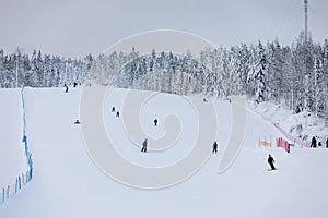 Skiers and snowboarders on a snowy slope in a ski resort in Finland.