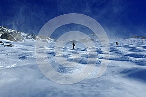 Skiers in a storm of blown snow