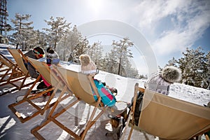 Skiers in sun bad sunbathing on ski terrain, back view