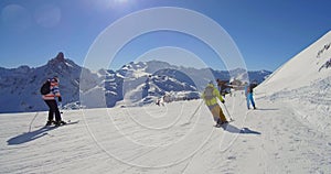 Skiers on sunny ski track in alpine mountains