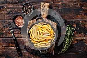Skilet full of Potato french fries with salt. Wooden background. Top view