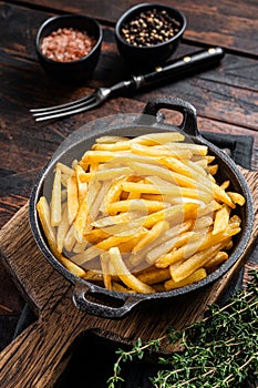 Skilet full of Potato french fries with salt. Wooden background. Top view photo