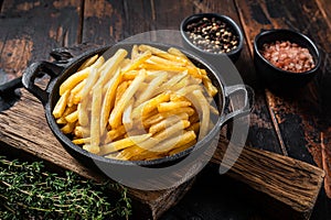 Skilet full of Potato french fries with salt. Wooden background. Top view