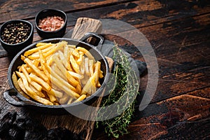 Skilet full of Potato french fries with salt. Wooden background. Top view. Copy space