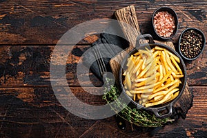 Skilet full of Potato french fries with salt. Wooden background. Top view. Copy space photo