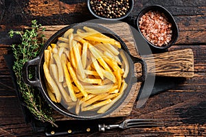 Skilet full of Potato french fries with salt. Wooden background. Top view photo