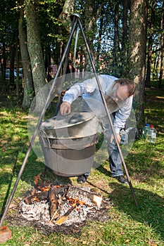 Skilful cook prepares soup over the fire