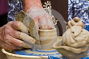 Skilful craftsman hands form a clay bowl on a traditional pottery wheel, ethnography study