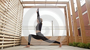 Skilled, adult woman exercising alone on a wooden terrace