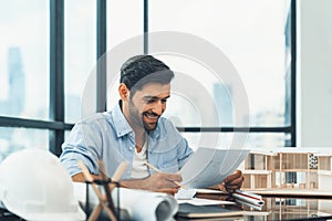 Skilled architect engineer holding blueprint on desk in modern office. Tracery.