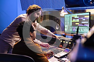 Skilled artist working with audio technician to edit recorded songs photo