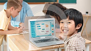 Skilled asian boy coding program and looking at camera in STEM class. Pedagogy.
