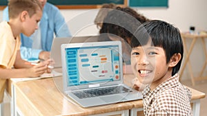 Skilled asian boy coding program and looking at camera in STEM class. Pedagogy.